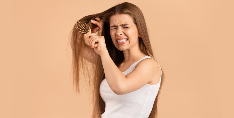 Frustrated young woman trying brush hair